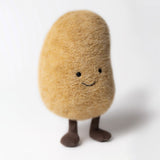A plush toy resembling a potato with a smiling face, made from golden-brown fur fabric with corduroy legs.