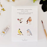 Set of paintable watercolor notecards with bird illustrations on a white surface.