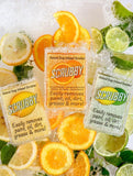Three Scrubby soap packages surrounded by citrus fruits.