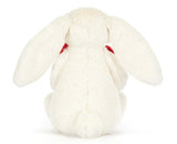 White plush bunny with big floppy ears holding a plush red heart.