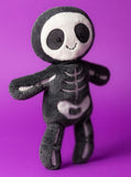 Skeleton plush toy with black and white design and a smiling face.