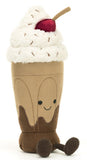 Plush toy resembling a chocolate milkshake with whipped cream and a cherry on top. It has a smiling face and brown corduroy legs.