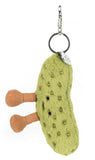 Plush green pickle bag charm with a smiling face and brown legs with a silver back clip.