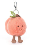 Plush peach keychain with a smiling face on a white background.