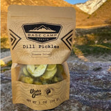 Bag of freeze-dried dill pickles with 'Base Camp Treats' branding. A small window on the front of the bag provides a view of the product.