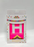 Package of a pink birthday banner with colorful text on a white background.