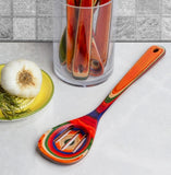 Colorful kitchen slotted spoon with a glass container and vegetables.