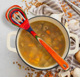 Pot of soup with a colorful slotted spoon.