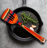 Colorful spatula on a cast iron skillet with herbs and garlic.